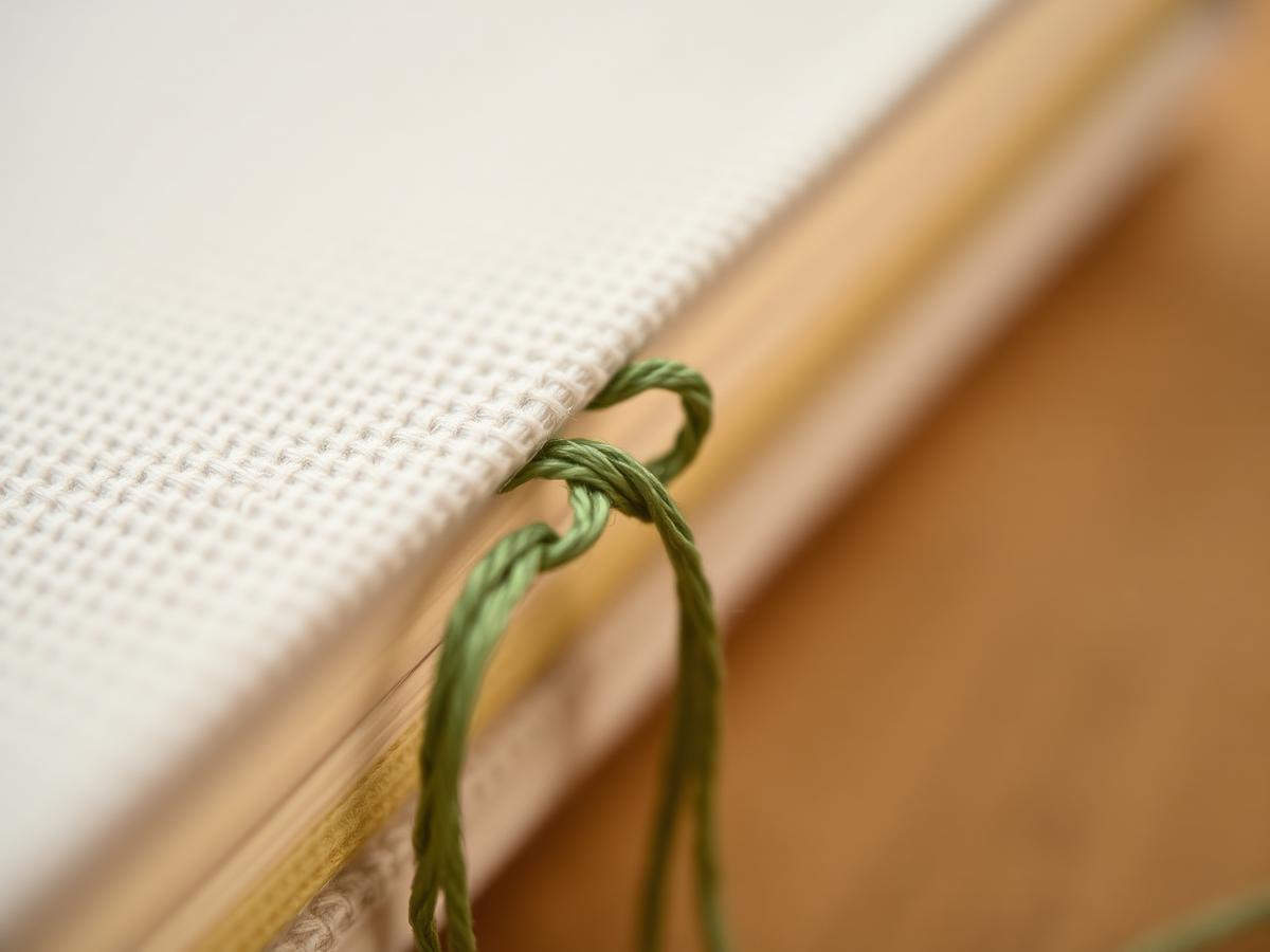 Macro close-up of sage green thread binding on a cloth-bound notebook